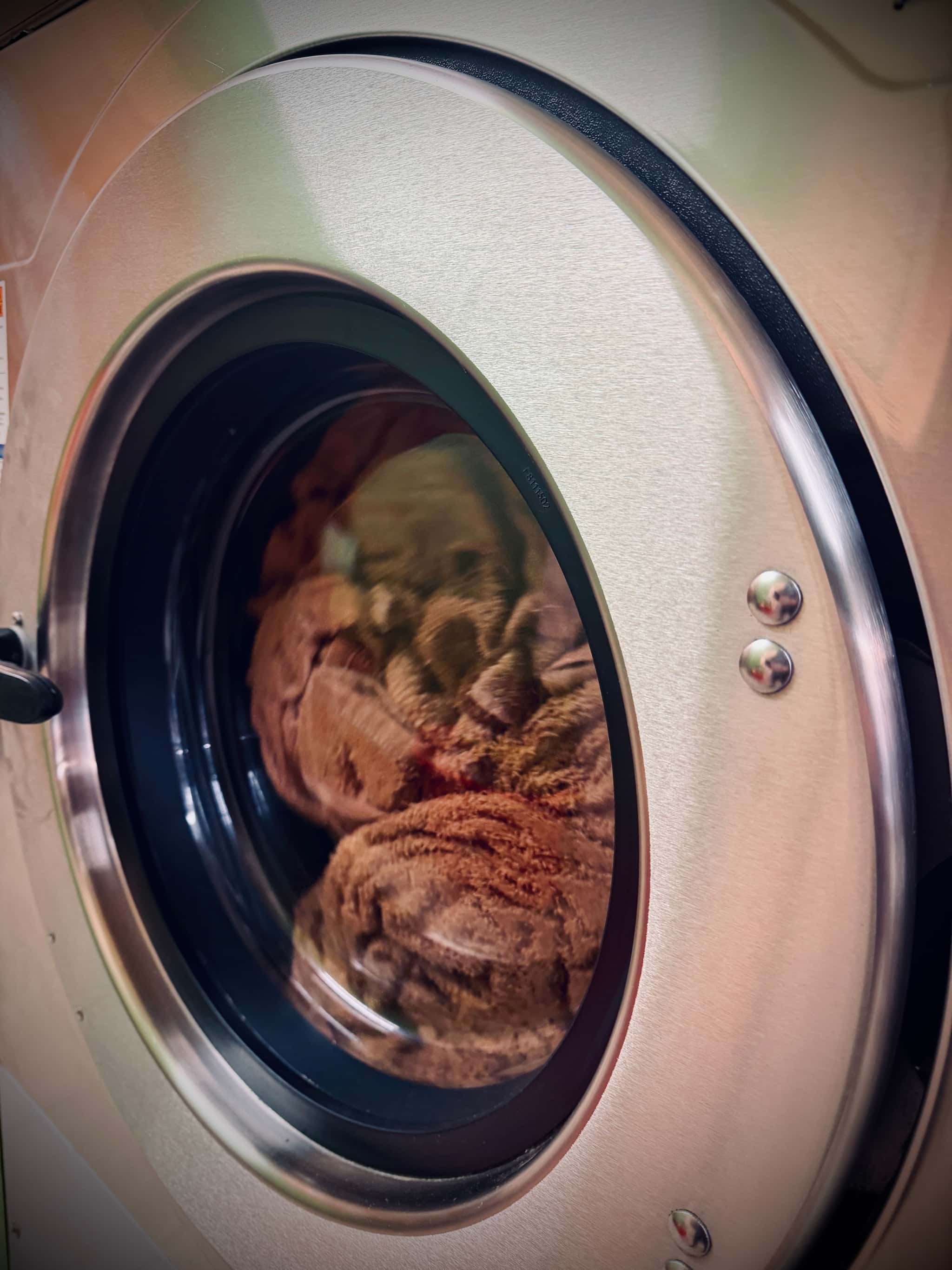 Large commercial washing machine mid-cycle at H&M Laundrette